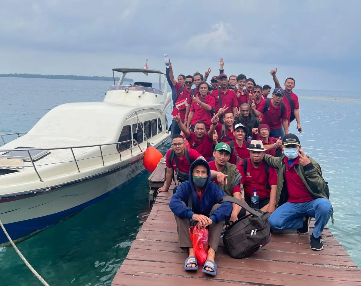 Rombongan corporate outing di dermaga dengan kapal